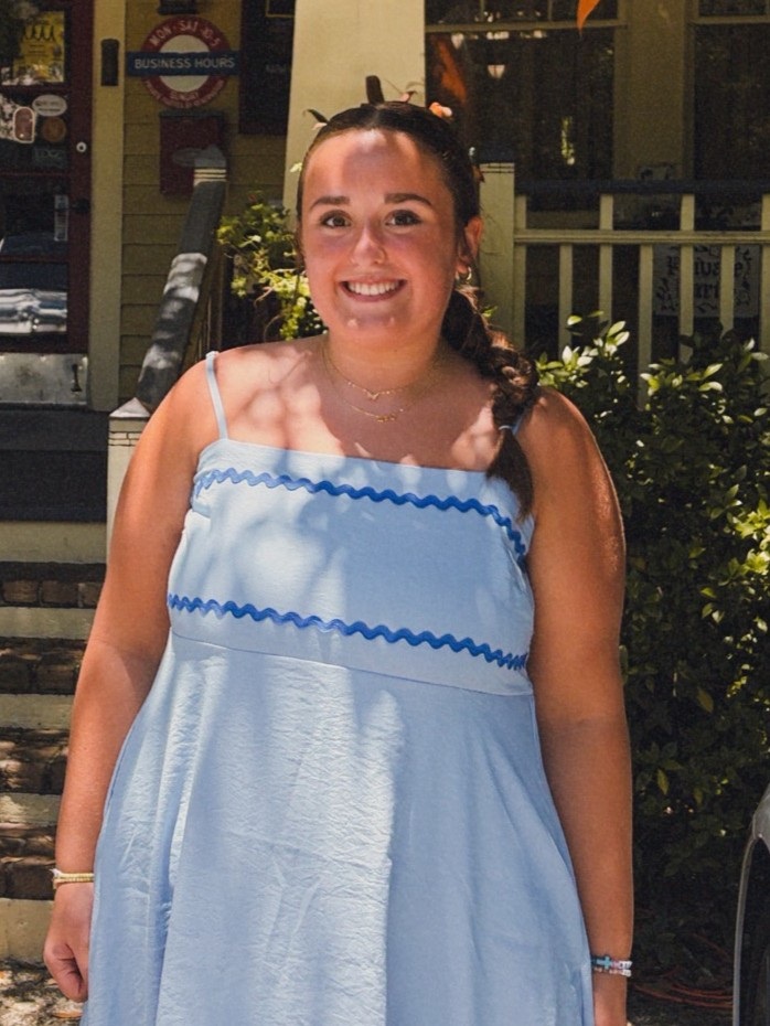Lelia smiling outdoors in a light blue dress